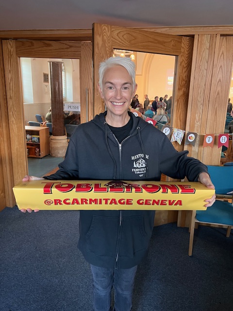 Author CJ Tudor is holding a giant Toblerone in front of her. It is nearly 1 metre wide and she is holding it in two hands, and she has a large smile.